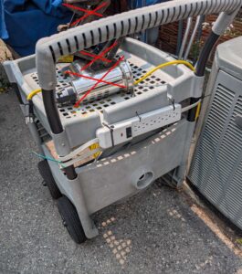 Plastic garden cart with extension cord & power bar.